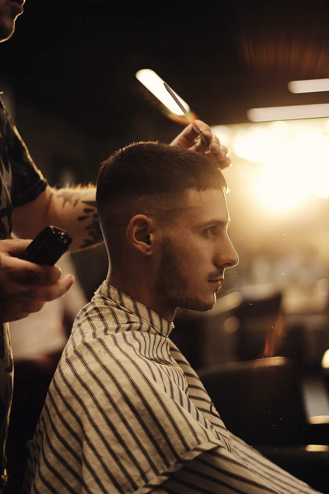 Barber finishing a skin fade under warm shop lights