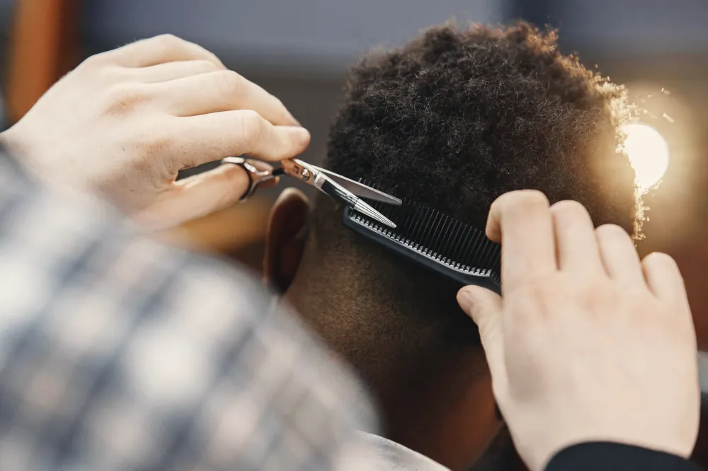 Barber shaping an Afro with comb and scissors