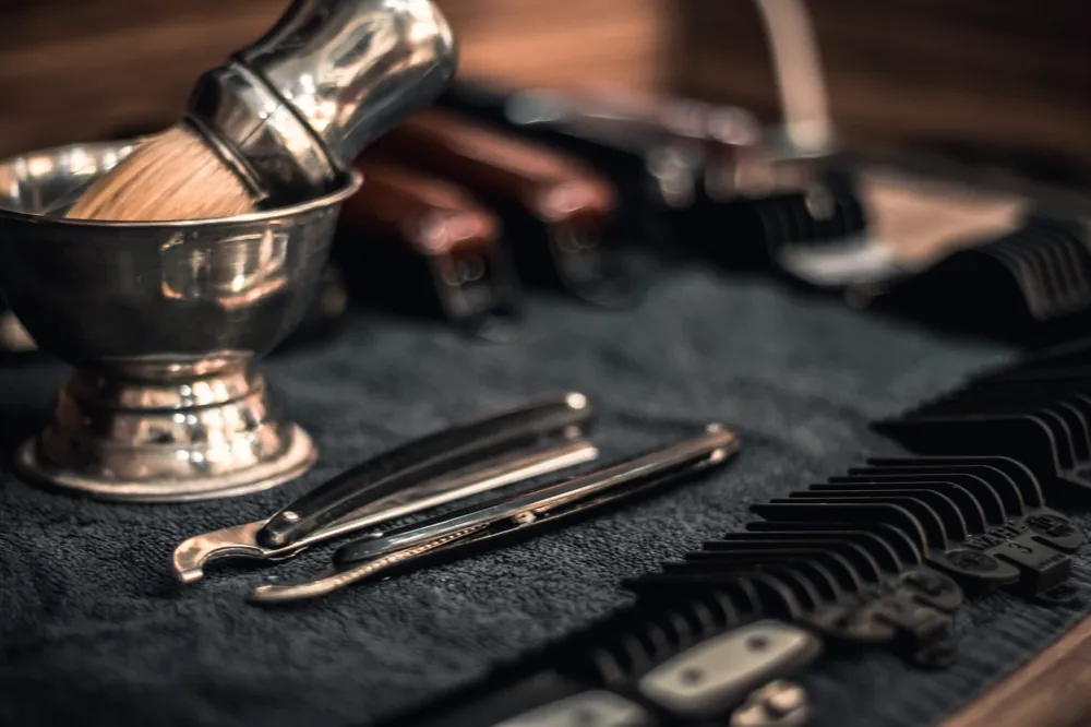 Straight razors, combs and shaving brush laid out on a towel
